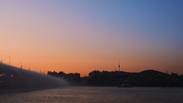 Sunset view of a city skyline by the river with bridge fountain