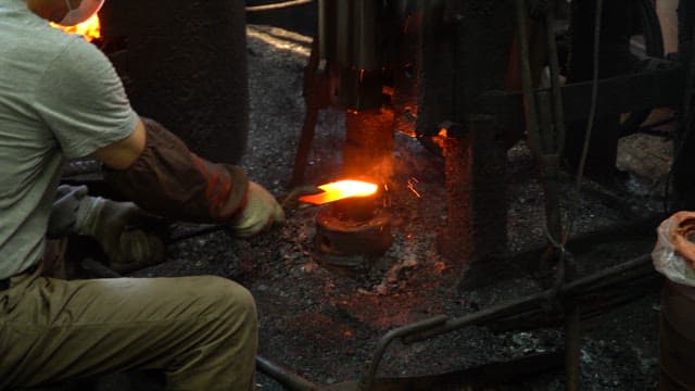 Worker forging metal in a factory