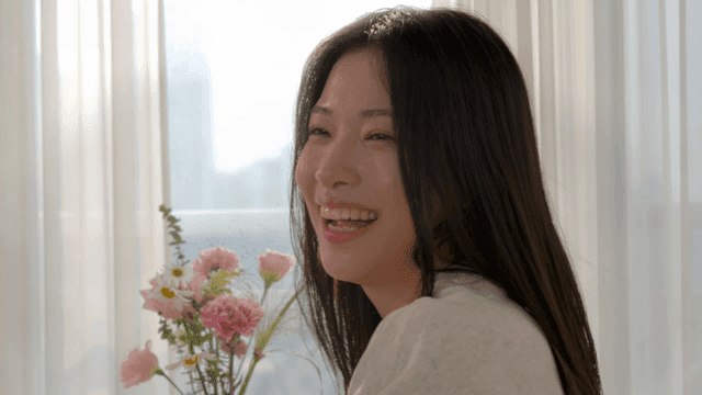 창가에서 꽃과 함께 미소 짓는 여성