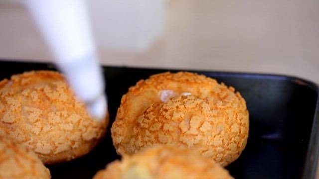 Filling cream puffs in a baking tray