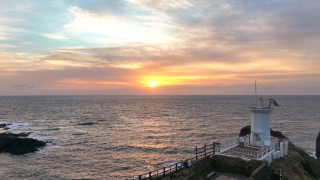 Lighthouse on a coastal cliff at sunset