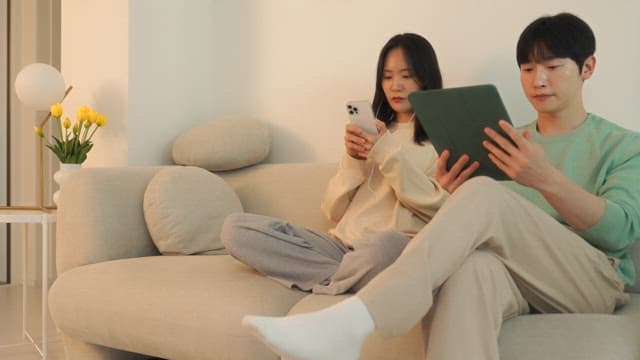 아늑한 거실 소파에서 디지털 기기를 사용하는 두 사람