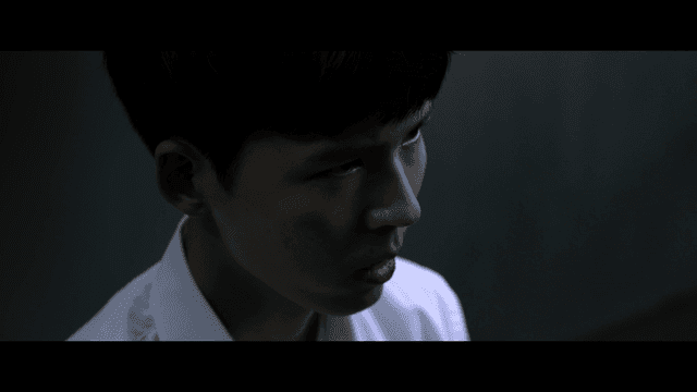 Young man speaking while standing in dark room