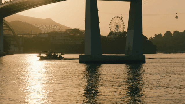 Bridge and Ferris wheel over sea at sunset