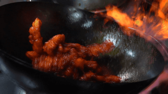 Sweet and sour pork stir-fried in wok with spicy sauce