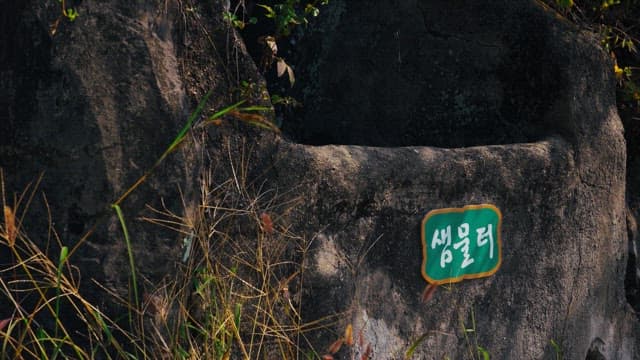 바위로 만들어진 오래된 샘물터의 초록색 이름표