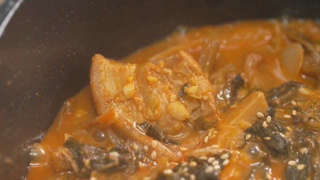 Simmering dried radish greens and pork belly stew in a pot