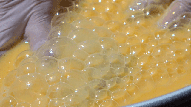 Gloved hand dipped in foamy egg mixture