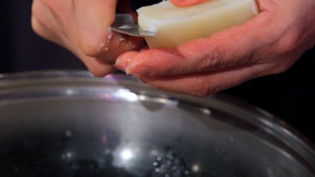 Slicing potatoes over chicken pieces