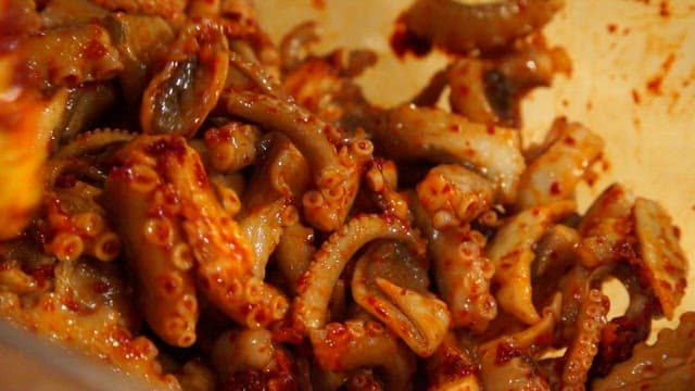 유리 그릇에서 매운 양념과 낙지를 섞는 모습