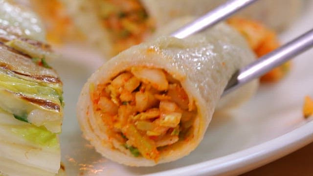 젓가락으로 잡은 배추 소가 들어간 메밀전병