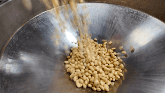 Soybeans falling into a metal grinder