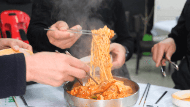 People scooping out spicy chicken stew ramen