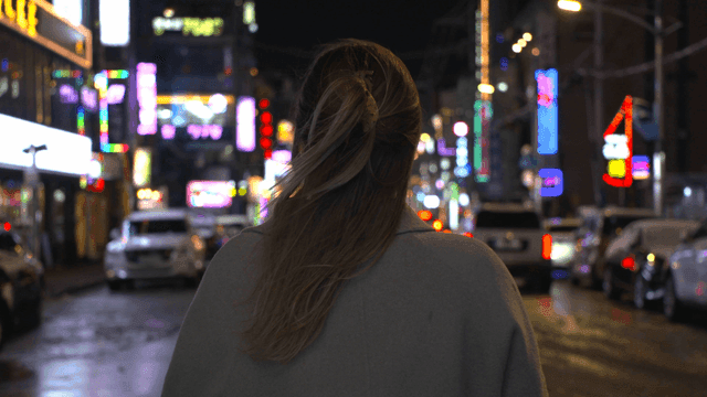 Back view of woman on lively night city street