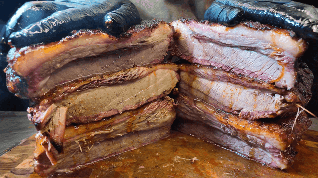 Hand pressing juicy smoked brisket