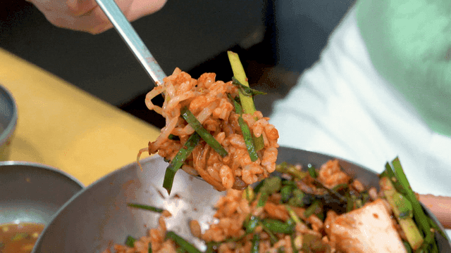 Spoon lifting gochujang bibimbap mixed with assorted vegetables