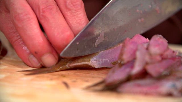 Slicing fresh damselfish on a wooden cutting board