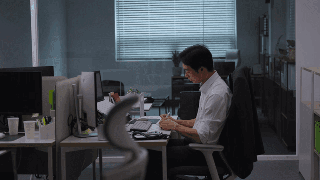 어두운 사무실 책상에 앉아 야근하는 직장인