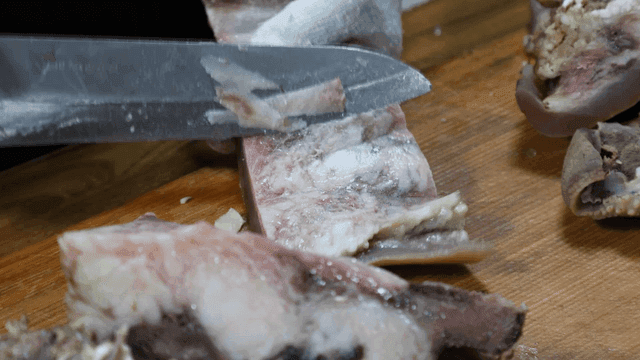 Head meat being sliced ​​on wooden cutting board