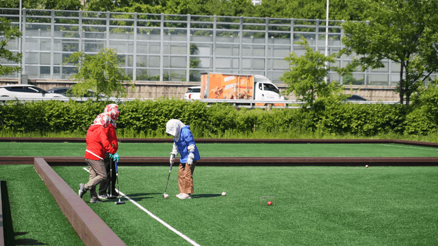 Old people playing croquet in park