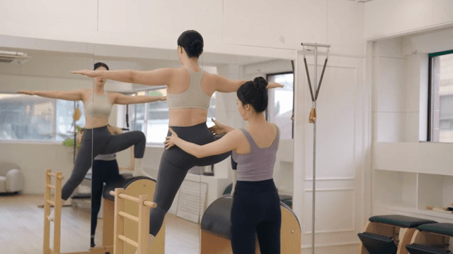 Pilates instructor guiding a student indoors