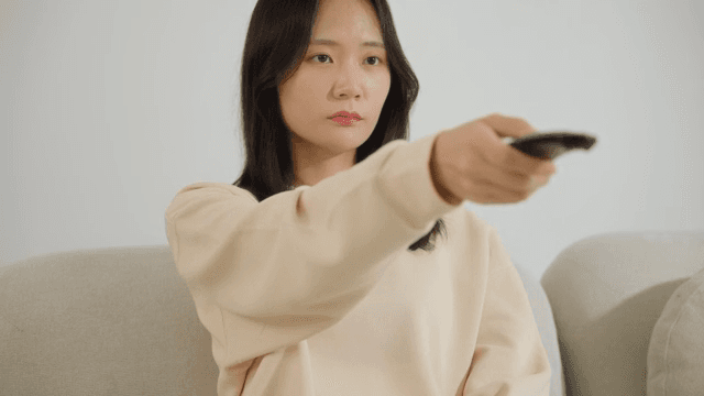 소파에서 리모컨을 조작하는 여자