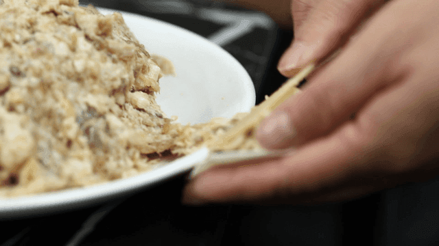 Dumpling filling placed into wrapper by hand