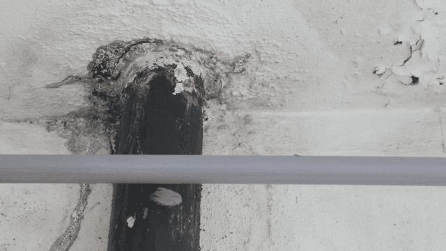 Close-up of a damaged wall with a pipe