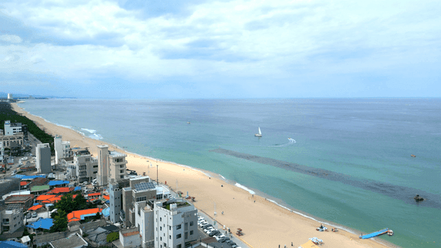 Tranquil beach with yachts and jet skis visible in distance