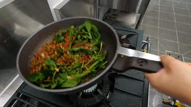 Stir-frying spinach and minced meat in a pan