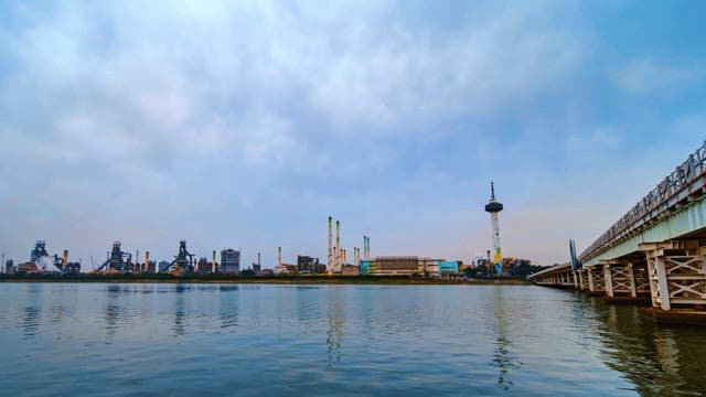 낮에서 밤으로 변하는 강변의 산업 도시 풍경