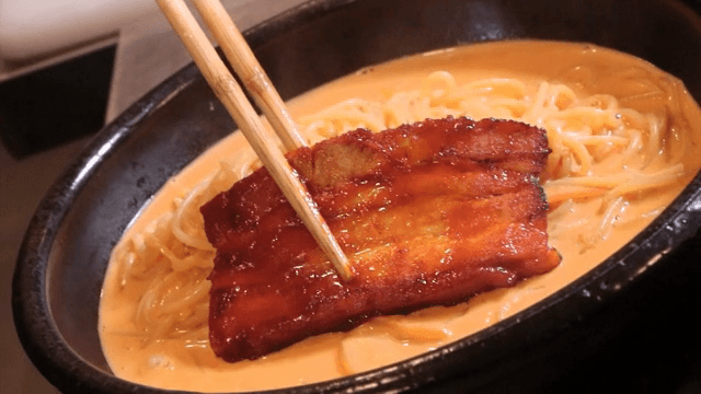 Topping the pasta with seasoned pork