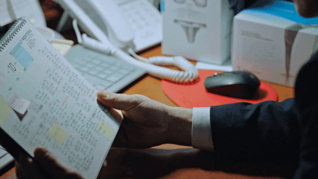 Male office worker checking dense calendar at dark office desk