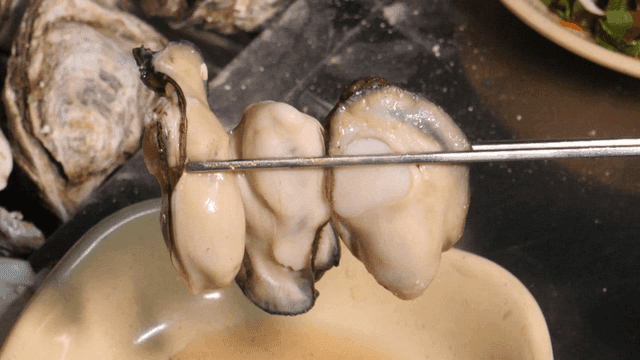 Fresh oysters being prepared with chopsticks