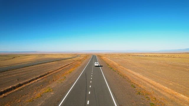 Solo Vehicle Traveling along a Vast Desert Road