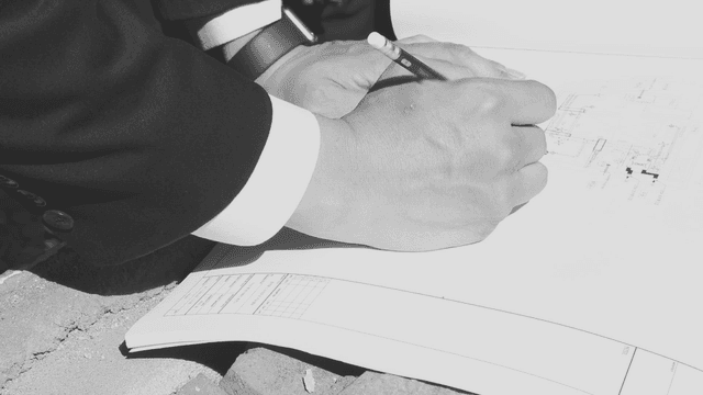 A person writing on architectural plans