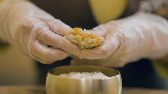 Preparing soy sauce marinated crab on rice with hands wearing vinyl gloves