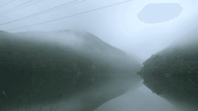 Misty lake surrounded by forested hills