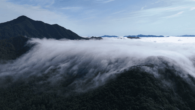 Clouds rolling over lush green mountains