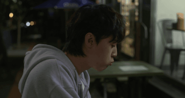 Young man spitting out skewers and soju while drinking outside convenience store