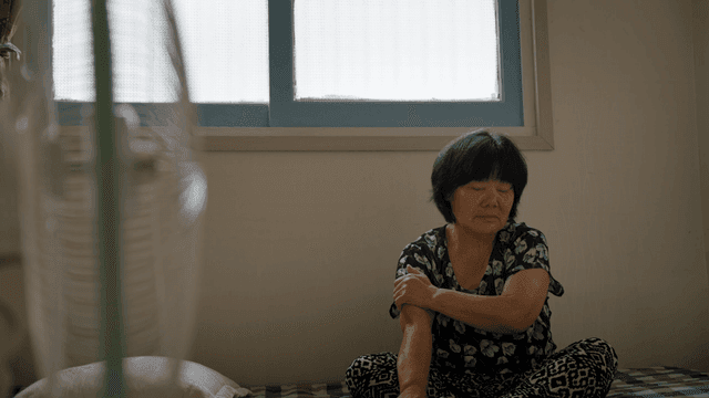 선풍기가 있는 방에 앉아 있는 노인 여성