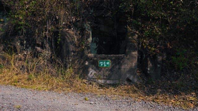 Green name tag for an old spring water site made of rock