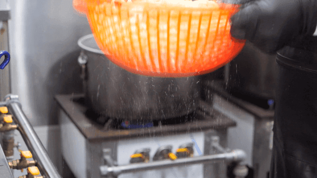 Chef biting into noodles in kitchen