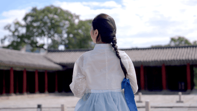 Woman in traditional Korean attire at a historic site