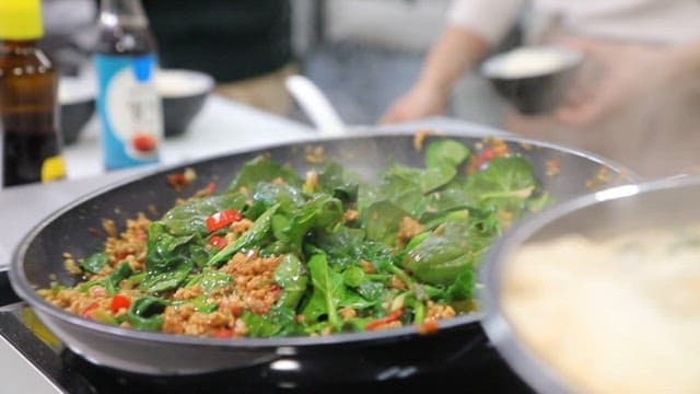 부엌에서 뜨거운 팬에 시금치와 밥을 볶는 모습