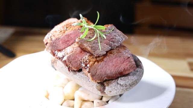 하얀 접시에 돌과 함께 플레이팅된 고급 스테이크