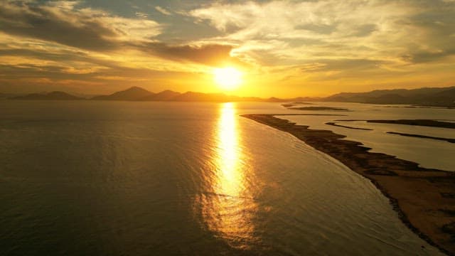 Sunset over a calm sea with distant mountains