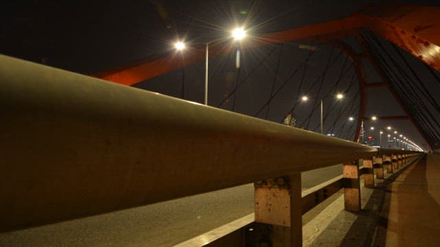 밤의 불 켜진 다리 위를 지나가는 차 조명의 궤적