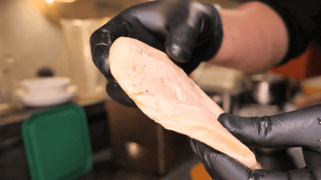 Hand holding firm chicken breast