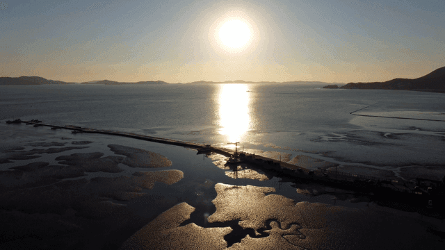 Sunset over a tranquil sea with a pier